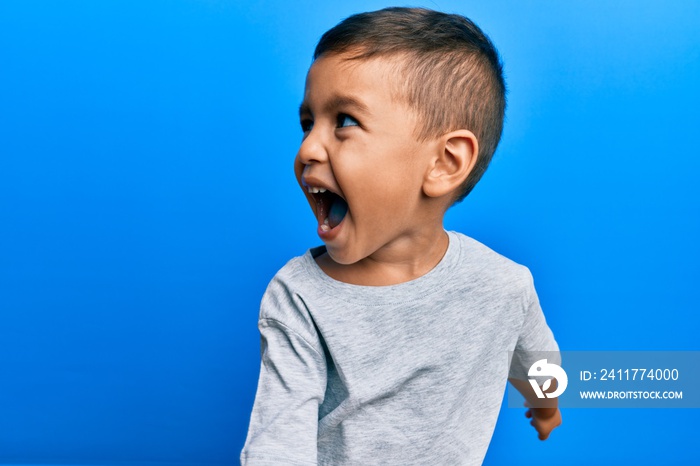 Adorable latin toddler smiling happy standing over isolated blue background.