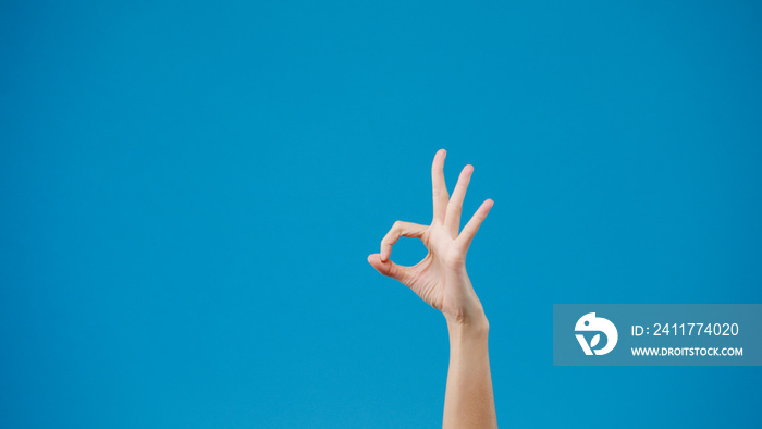 Young woman hand showing ok sign with fingers isolated over blue background in studio. Copy space for place a text, message for advertisement. Advertising area, mock up promotional content. Close up.