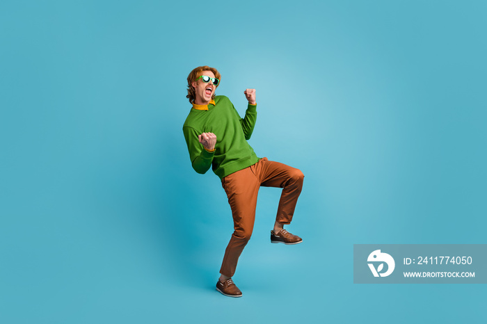 Full size photo of young happy excited crazy positive man in sunglasses dancing in victory isolated on blue color background