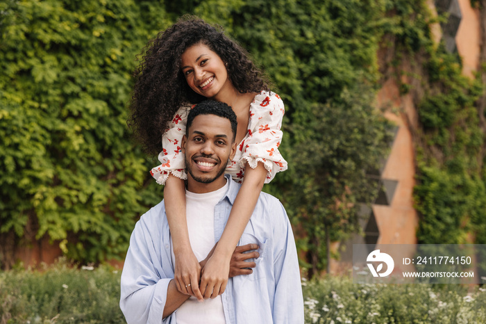 Cute young african couple in love posing looking at camera spending leisure time in nature. Guy and brunette girl enjoy each other. Relaxed lifestyle, concept