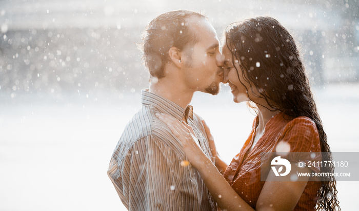 Two lovers kissing under summer rain