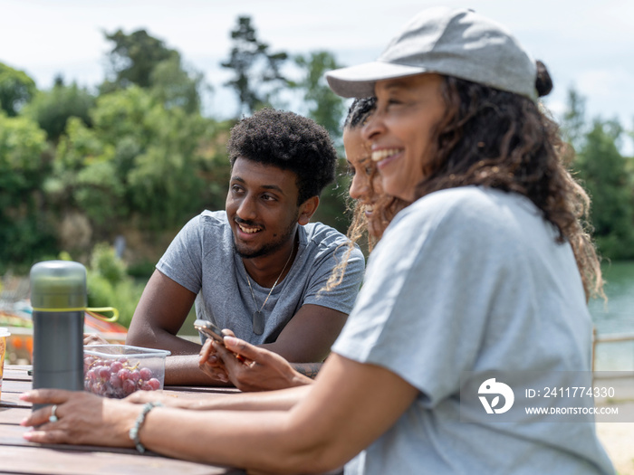 Friends laughing during picnic by lake