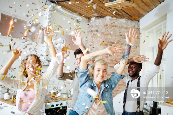 Ecstatic friends raising hands during dance under confetti fall