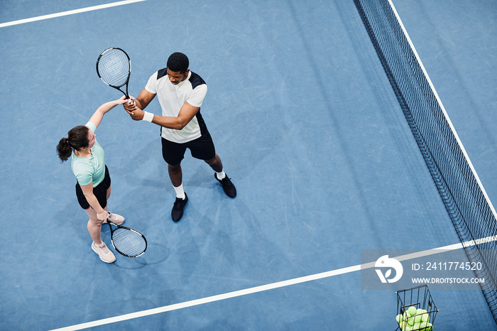 Minimal top view of tennis coach working with client against vibrant blue court, copy space