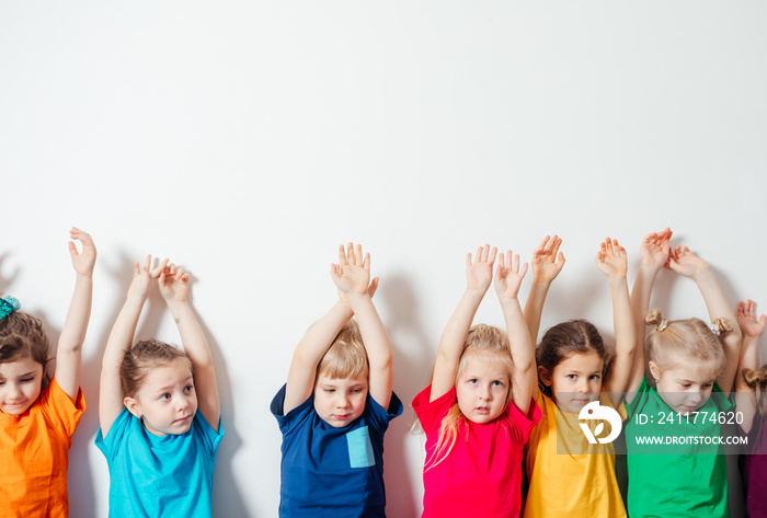 Children holding hands up on white wall background