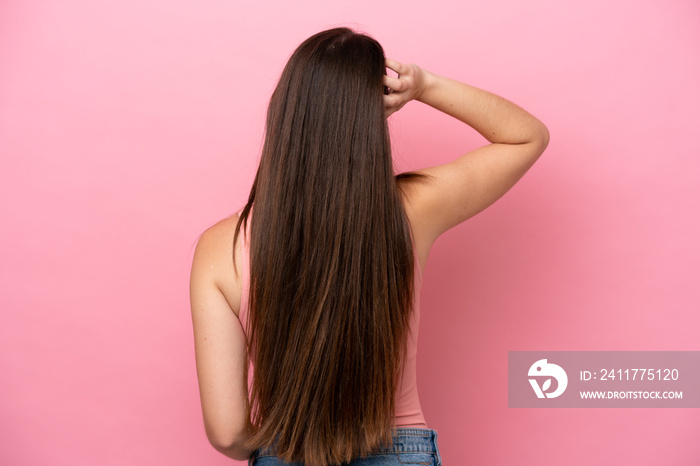 Young caucasian woman isolated on pink background in back position and thinking