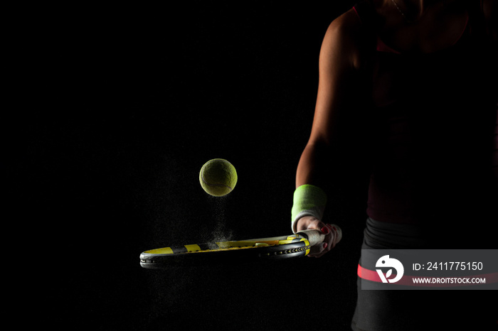 Tennis ball bouncing on racket. Dirt or magnesium dust dots visible in the air. Female player holding racket