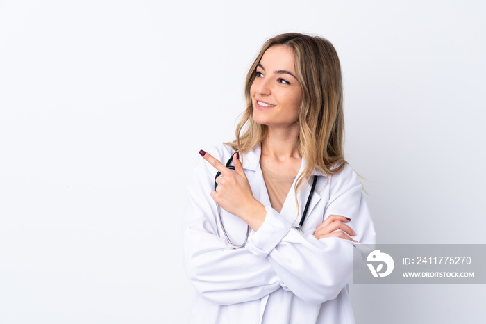 Young woman over isolated white background wearing a doctor gown and pointing side