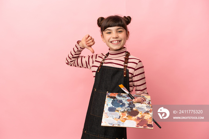 Little artist girl holding a palette isolated on pink background proud and self-satisfied