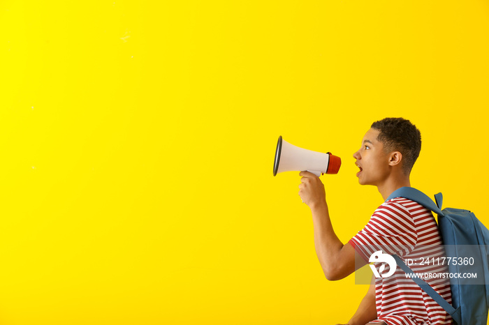 Portrait of African-American teenage boy with megaphone on color background