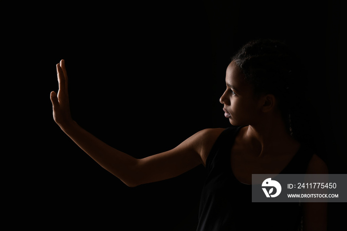 Sad African-American girl on dark background. Stop racism