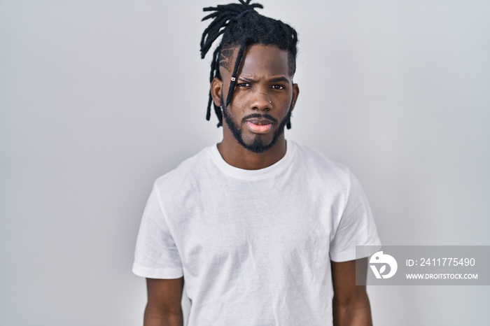 African man with dreadlocks wearing casual t shirt over white background skeptic and nervous, frowning upset because of problem. negative person.