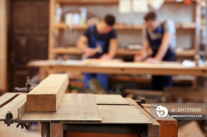 Table in workshop and blurred carpenters on background