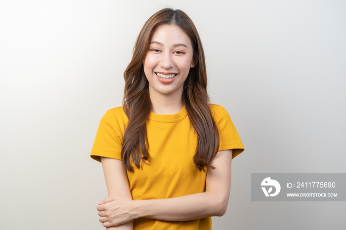 Smile positive, attractive asian young woman wearing yellow casual, portrait of beautiful brunette her with long hair, cute girl feeling happy, standing cross arms chest isolated on white background.