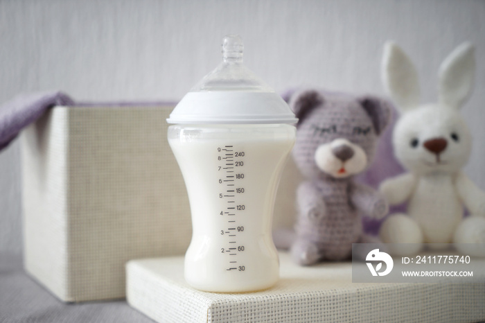 Bottle of milk with baby toys on table