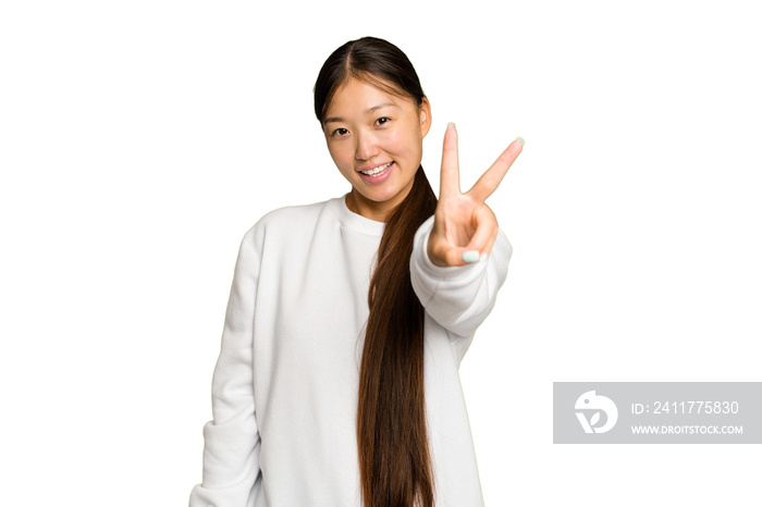 Young Asian woman isolated on green chroma background joyful and carefree showing a peace symbol with fingers.