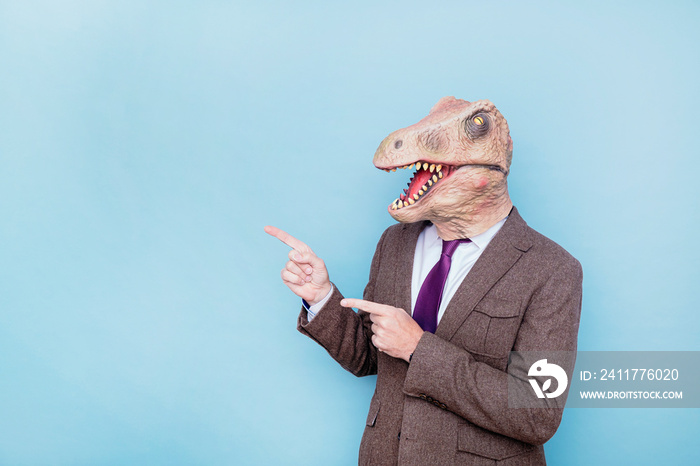 Euphoric man with lizard head pointing to the side on blue background.