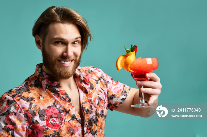 Young man in hat and sunglasses drinking margarita cocktail drink juice happy looking at camera laughing over light green