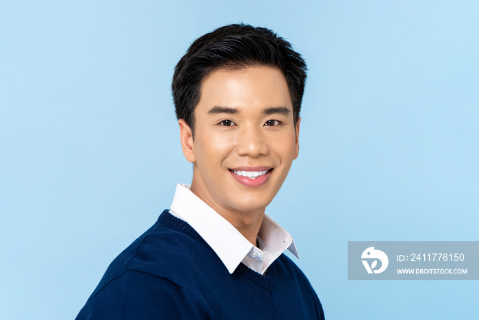 Close up portrait of young handsome smiling Asian man face on light blue studio background