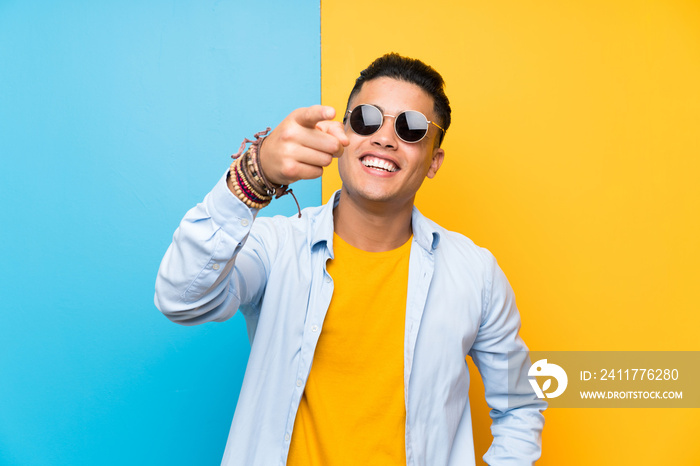 Young man over isolated colorful background with sunglasses