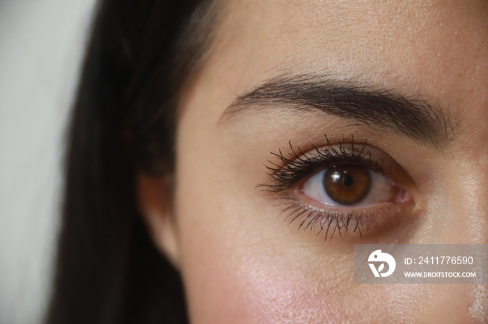 Woman’s hazel eye, light brown, black eyelashes, looking at the camera.