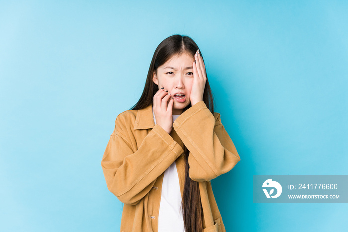 Young chinese woman posing in a blue background isolated whining and crying disconsolately.