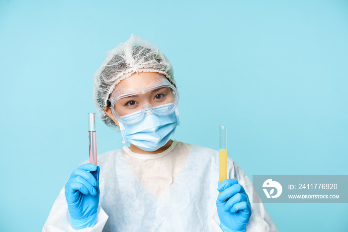 Laboratory and medical tests concept. Smiling asian female doctor, lab worker showing tubes with clinical testing products, blue background