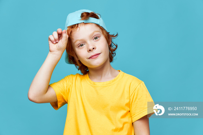 Cheerful redhead boy in blue cap yellow T-shirt fashionable clothes isolated he