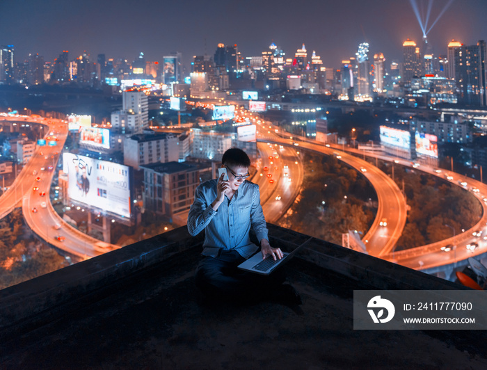 Asian man using phone and laptop with city  background, technology communication concept