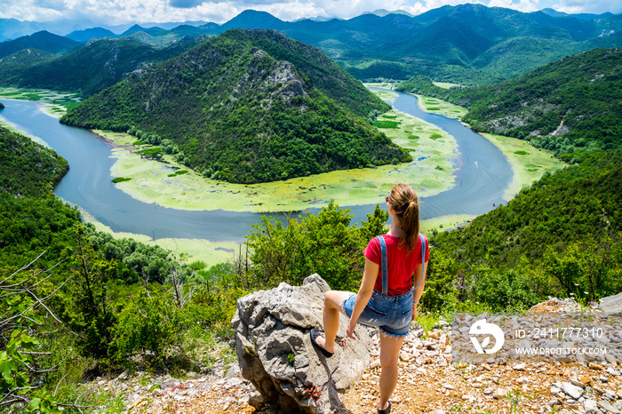 Montenegro, Gorgeous young woman with long hair standing at rock above crnojevica river water bend in green canyon national park skadar lake nature scenery