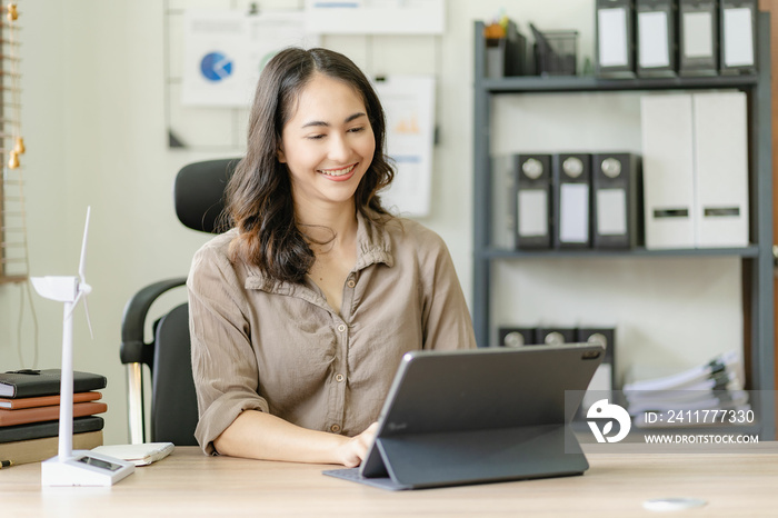 Asian woman holding a windmill Simulate wind energy examples and advice on alternative energy in an online meeting in front of a tablet computer in the office.