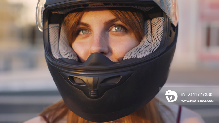 beautiful young red-haired woman motorcyclist with black motorcycle helmet