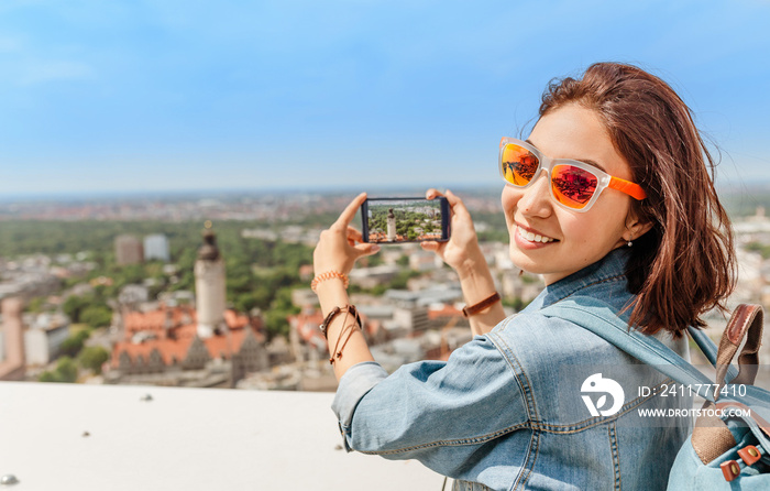 Happy young woman tourist traveler looking at the city view of Leipzig from a bird’s eye view from the viewpoint