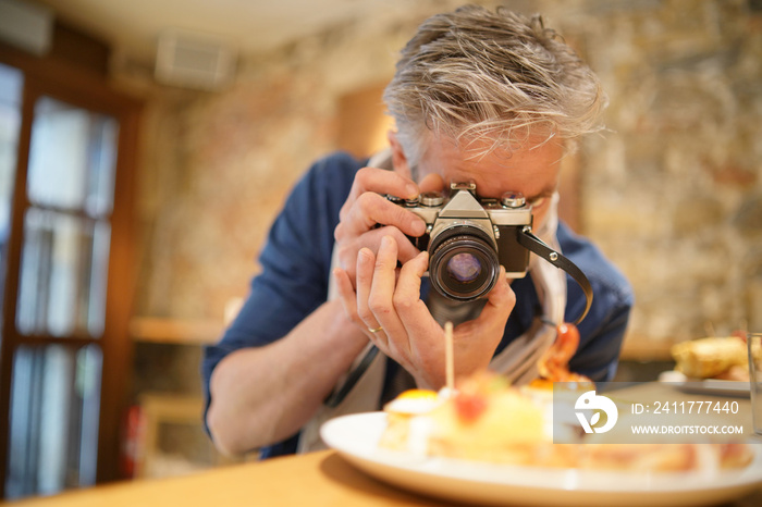 Mature photographer taking photos of tapas plate in Spanish restaurant