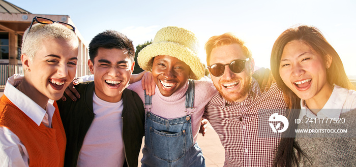 Smiling panoramic portrait of cheerful group of young people. Happy friends excited having fun. Interracial boys and girls taking picture looking at camera smart mobile phone. Enjoying vacations