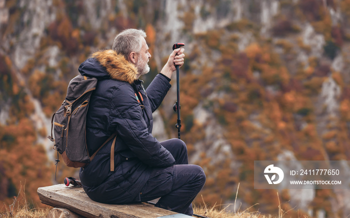 Happy mature man on a hiking resting on a bench and enjoy the view