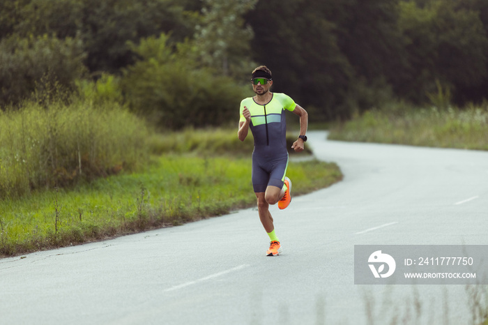 Young professional male triathlete, runner in motion on open road. Concept of sport, lifestyle, activity