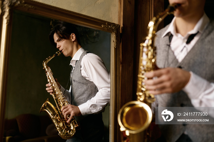 Young man playing saxophone in reflection of mirror at home