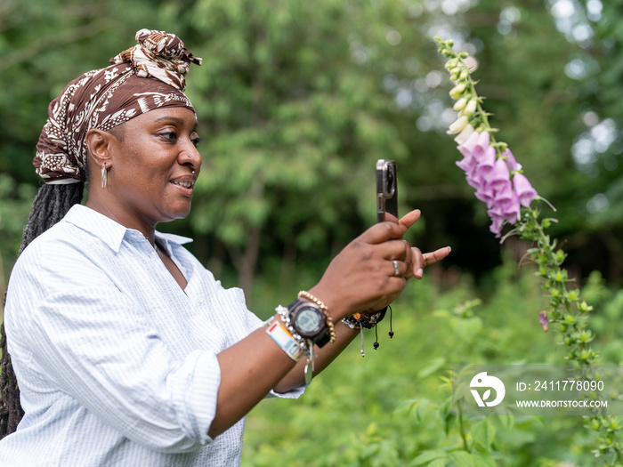 Mature woman photographing flowers in garden