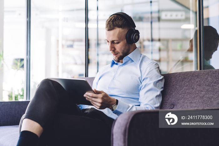 Man with headphones sitting in office and using tablet