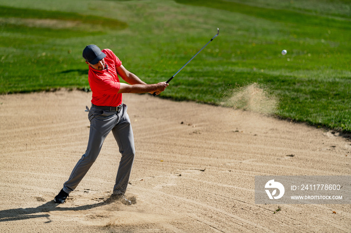 Golfing shot from sand, professional golf player playing from a sand bunker, golf ball in the air