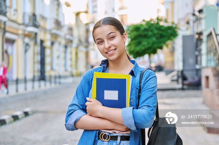 Outdoor portrait of smiling teenage female student looking at camera in city