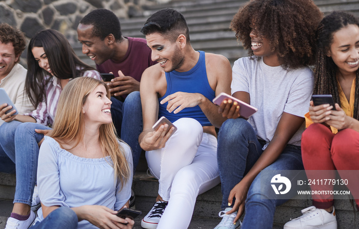 Multiracial people having fun together in the city while using mobile phones