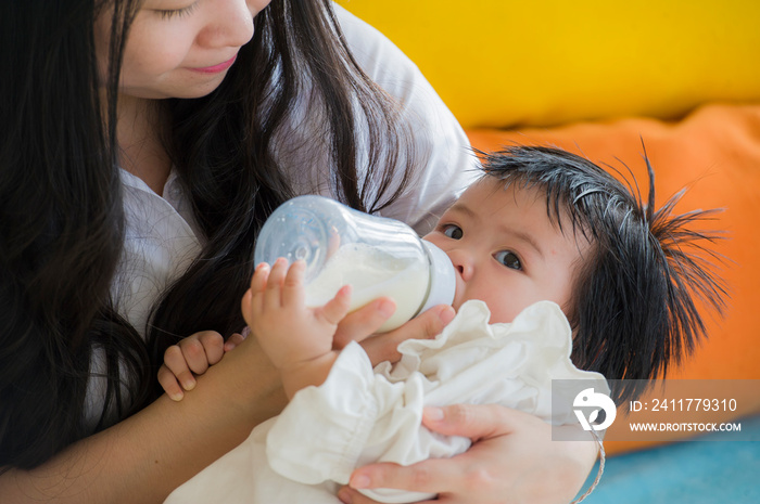 lifestyle candid portrait of young happy and sweet Asian Korean woman feeding her beautiful baby girl with formula bottle at holidays resort as mother nursing daughter