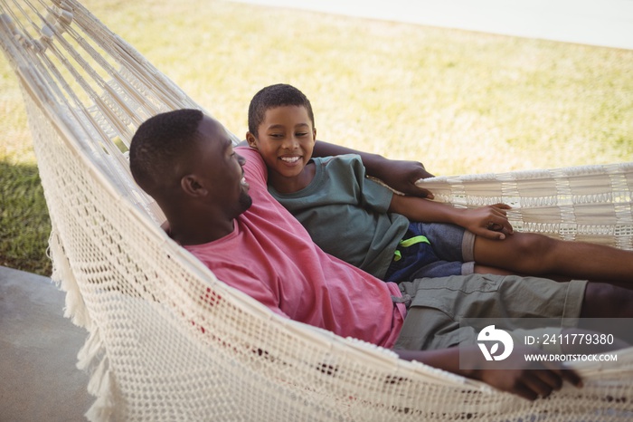 Smiling father and son relaxing on a hammock