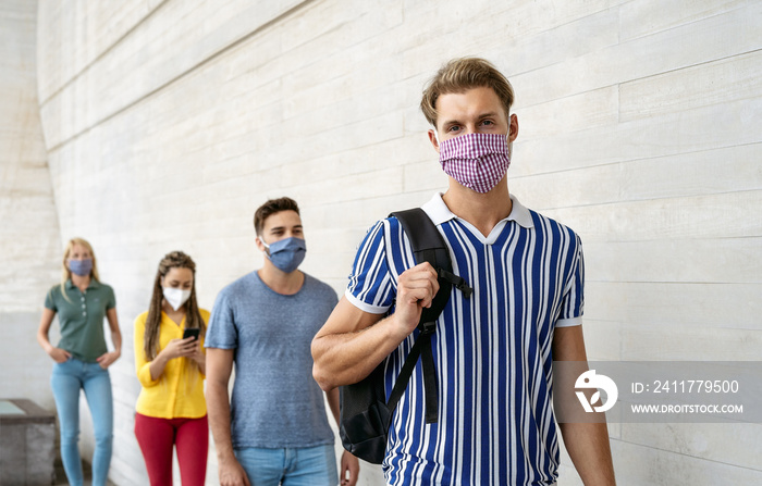 Young people from different cultures and race waiting in queue outside shop market while keeping social distance - Corona virus spread prevention concept