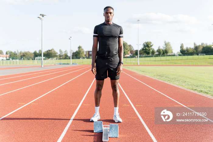 Athlete standing in front of starting line at running track