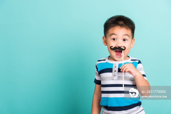 Funny happy hipster kid holding black mustache props for the photo booth close face, studio shot isolated on a blue background, Men health awareness, Prostate Cancer Awareness