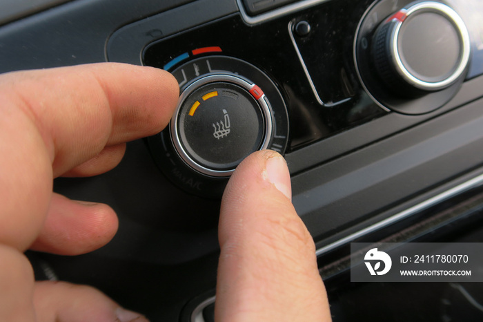 Winter Herbst Autofahrer drückt taste Sitzheizung  im Auto Interieur