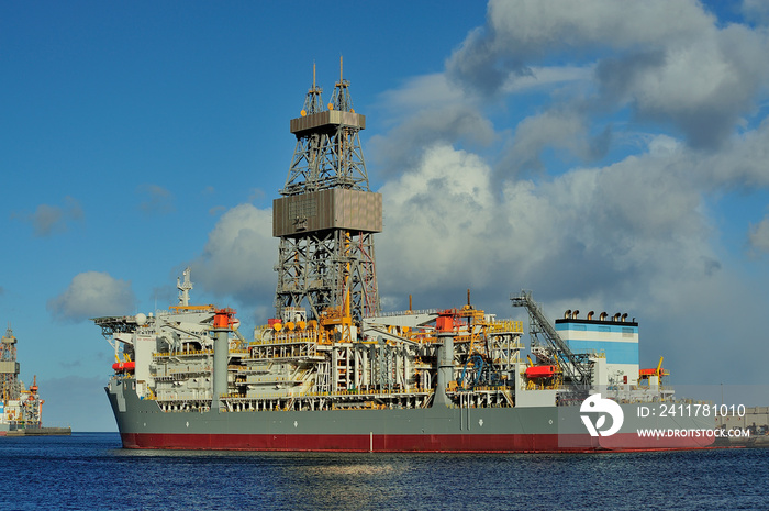 Drilling ship moored in port with a cloudy day.